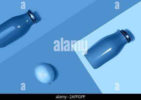 Flaschen bunte Säfte oder Smoothies und Zitrone auf trendy Classic blau Hintergrund. Flach, Ansicht von oben, aus der Nähe. Minimalistischer Stil. Classic blau Farbe des Jahres Inschrift 2020. Stockfoto