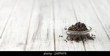 Erhaltene schwarze Pfefferkörner auf hölzernen Hintergrund; selektive Fokus, Nahaufnahme Stockfoto