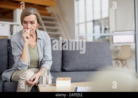 Portrait von traurigen reife Frau auf der Couch zu Hause sitzen und weinen Holding Gewebe, kopieren Raum Stockfoto
