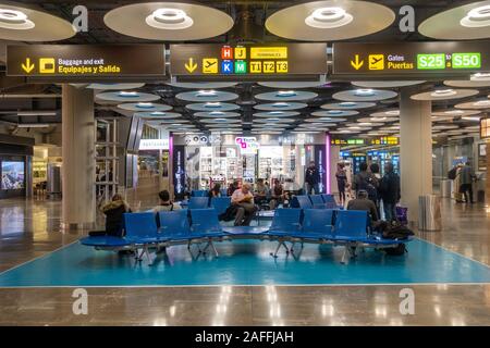 Die Leute sitzen auf den Sitzen in der Abfahrt am Terminal 4 S von Adolfo Suárez Flughafen Barajas in Madrid, Spanien. Stockfoto