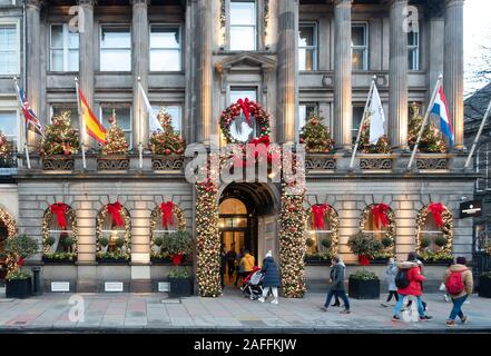 Die Menschen verlassen, und das InterContinental Hotel auf der George Street im Zentrum von Edinburgh, Schottland. Vor dem Hotel ist für Weihnachten mit Weihnachten Bäume auf Balkon, einen großen Kranz über der Tür dekoriert, und Girlanden mit roten und goldenen Kugeln und roten Bändern. Stockfoto