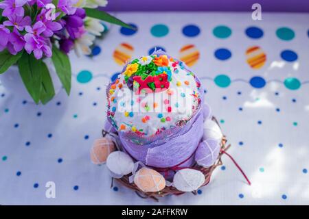 Hausgemachte Kuchen mit bunten Süßigkeiten und ukrainischen Buchstaben XB eingerichtet. Bemalte Eier im Korb um Kuchen für Ostern auf Tisch mit schönen Easte Stockfoto