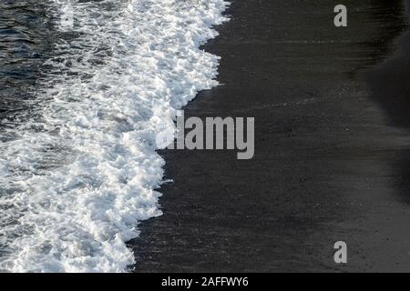 Wellen auf einem Black Sand Beach Stockfoto