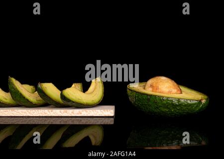 Gruppe von Halb vier Scheiben frischen grünen Avocado auf Holz Schneidebrett auf schwarzem Glas isoliert Stockfoto
