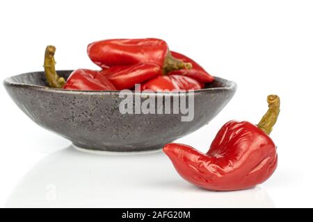 Menge ganze eingelegte rote Paprika in glasierte Schüssel auf weißem Hintergrund Stockfoto