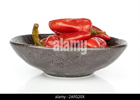 Menge ganze eingelegte rote Paprika in glasierte Schüssel auf weißem Hintergrund Stockfoto