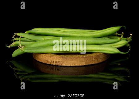 Menge ganze Snap grüne Bohne auf runden Bambus Untersetzer auf schwarzem Glas isoliert Stockfoto