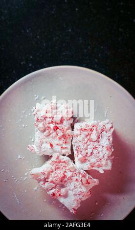 Marshmallows auf einem Teller mit zerquetschten Zuckerstangen Stockfoto