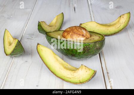 Gruppe von Halb vier Scheiben frischen grünen Avocado auf weißem Holz Stockfoto