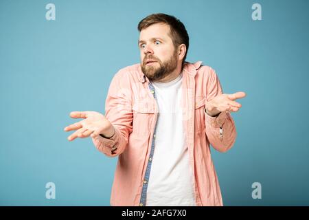 Bärtiger Mann ist verwirrt und durcheinander wirft Hände und zuckt mit den Schultern, auf die Seite. Stockfoto