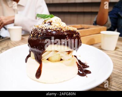 Hausgemachte fluffy Pancake und süße Sirup/leckere Pfannkuchen mit Schokoladensauce und Eis auf Esstisch im Cafe Restaurant Stockfoto