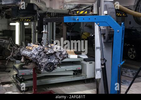 V8-Triebwerk mit acht Zylindern auf einem Kran für die Überholung Reparatur und Installation auf einem Auto nach einer Panne im Fahrzeug ausgesetzt worksh montiert Stockfoto