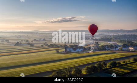 Heißluftballon erhebt sich in die Luft über amerikanische Landschaft in Pennsylvania, Airborne Luftschiff über Ackerland Stockfoto