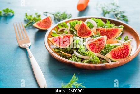 Herbst Salat von Rucola, Feigen in braunem Steingut Teller auf einem blauen Hintergrund. top View Stockfoto