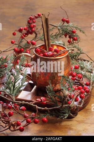 Glühwein auf einer hölzernen Hintergrund mit Tannenzweigen und Beeren. Stockfoto