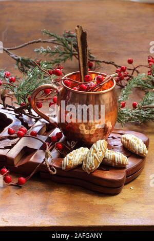 Glühwein auf einer hölzernen Hintergrund mit Tannenzweigen und Beeren. Stockfoto