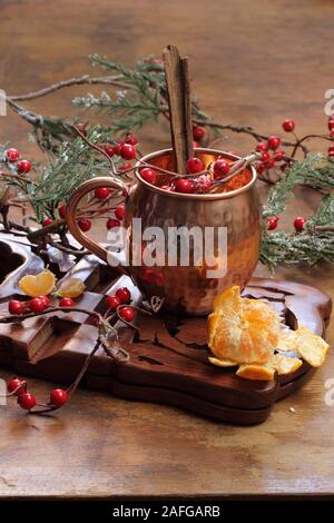 Glühwein auf einer hölzernen Hintergrund mit Tannenzweigen und Beeren. Stockfoto