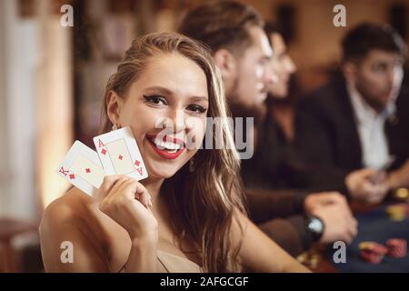 Mädchen mit Karten in ihren Händen lächelt Winning Poker in einem Casino. Stockfoto