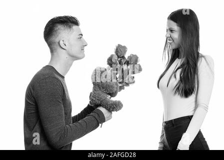 Junge glückliches Paar lächelnd und in der Liebe mit Mann, rote Rosen und Teddybär Stockfoto