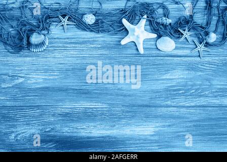 Fischernetz mit Seestern auf einer hölzernen Hintergrund getönten Classic blau Farbe Stockfoto