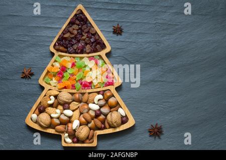 Weihnachtsbaum mit Nüssen und Trockenfrüchten auf dunklem Hintergrund Stockfoto