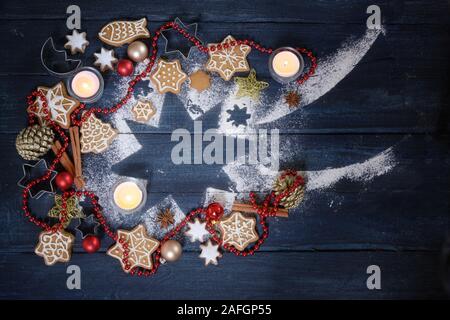 Falling Star Form aus Puderzucker, Weihnachtsdekoration, Gingerbread cookies und brennende Kerzen auf einem dunkelblauen Hintergrund Holz, hohe Betrachtungswinkel Stockfoto