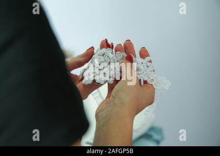 Eine Frau hält die Hochzeit Strumpfband in den Händen. Ein Detail aus der Zeremonie die Vorbereitungen. Stockfoto