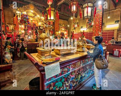 Frau setzt Räucherstäbchen am Altar in Man Mo Tempel für die zivile Gott Mann Tai und der kriegerische Gott Mo Tai. Sheung Wan, Hong Kong. Stockfoto