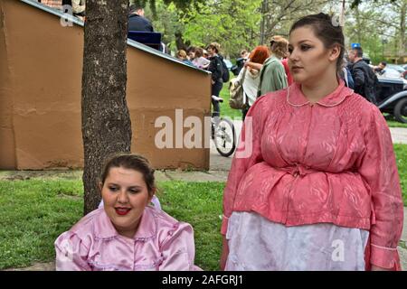 Ivanovo, Serbien, 15. April 2018. Traditionell gekleidete zwei junge Mädchen in den Schatten eines Baumes. Eine Versammlung der Fotografen ist in Ihrem plac gehalten Stockfoto