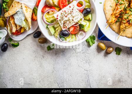 Griechisches Essen: Griechischer Salat, Hühnchen Souvlaki, Gyros Pita auf grauem Hintergrund, Ansicht von oben. Traditionelle griechische Küche Konzept. Stockfoto