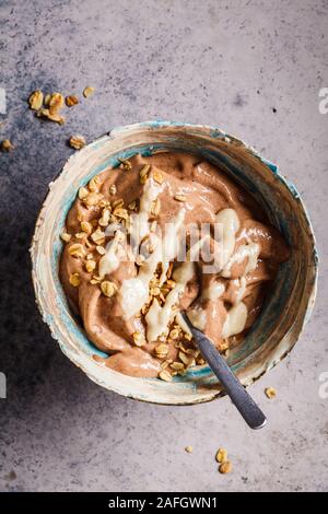 Veganes Frühstück. Schokolade Banane nicecream mit Müsli und Erdnussbutter. Stockfoto