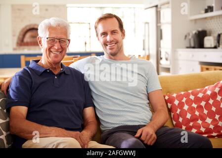 Portrait von lächelnden Vater mit erwachsenen Sohn Entspannen auf dem Sofa zu Hause Stockfoto