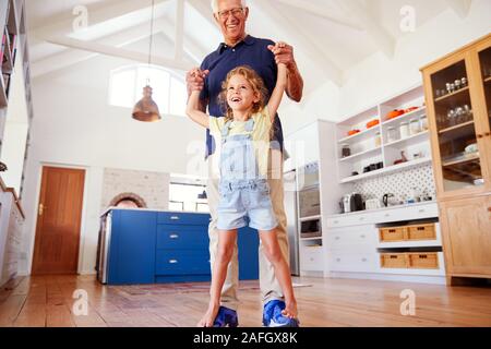 Enkelin, die Spiel zu Fuß auf der Großväter Füße zu Hause Stockfoto