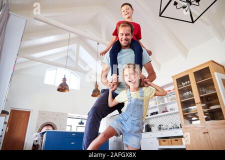 Tochter spielen Spiel gehen auf Väter Füße mit Sohn auf den Schultern zu Hause Stockfoto