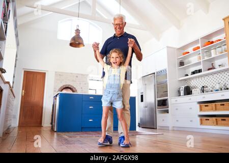 Enkelin, die Spiel zu Fuß auf der Großväter Füße zu Hause Stockfoto