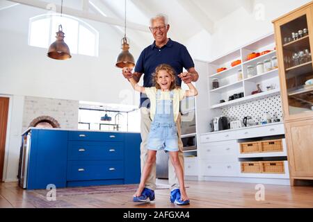 Enkelin, die Spiel zu Fuß auf der Großväter Füße zu Hause Stockfoto