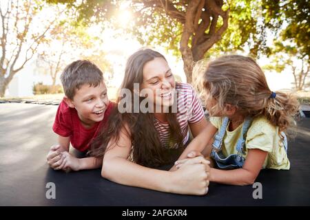Geschwister mit Jugendlichen Schwester Spielen auf Outdoor Trampolin im Garten Stockfoto