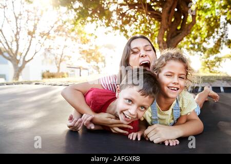 Portrait von Geschwistern mit Jugendlichen Schwester Spielen auf Outdoor Trampolin im Garten Stockfoto