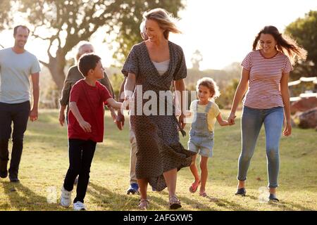 Multi-Generation Familie wandern in die Landschaft gegen das Abfackeln von Sun Stockfoto