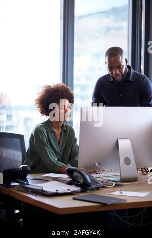 Junge schwarze männlichen und weiblichen Kollegen zusammen an einen Computer in einem kreativen Arbeiten im Büro, vertikal Stockfoto