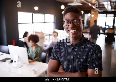 Tausendjährige männlichen Schwarzen kreative stehen in einem langen gemütlichen Büro, Lächeln für die Kamera Stockfoto