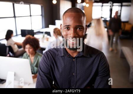 Bärtige männlichen Schwarzen kreative stehen in einem langen gemütlichen Büro, Lächeln für die Kamera Stockfoto