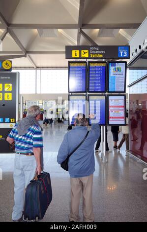 Zwei Menschen mit Koffern ständigen Lesen der Flight Information Display im Terminal 3 am Flughafen Malaga, Malaga, Spanien. Stockfoto