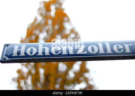 Nahaufnahme eines Straßennamens mit gelben Bäumen auf verschwommenem Hintergrund in München Stockfoto