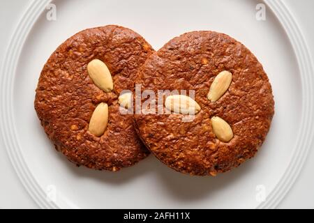 Stillleben mit ein Paar leckeren braunen Elisengingerbreads mit Mandeln liegen auf einem reinen weißen Porzellanteller Stockfoto