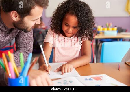 Grundschullehrer, die weiblichen Schüler Eins zu Eins Unterstützung im Klassenzimmer Stockfoto