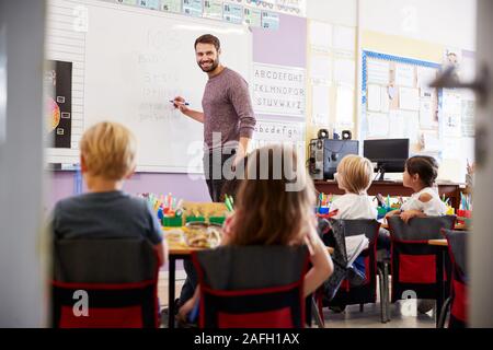 Männliche Lehrer am Whiteboard Lehre Mathe Lektion stehen Elementare Schülerinnen und Schüler In der Schule Klassenzimmer Stockfoto