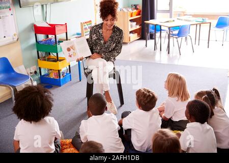 Lehrerin lesen Geschichte Gruppe von elementaren Schüler Uniform tragen In der Schule Klassenzimmer Stockfoto