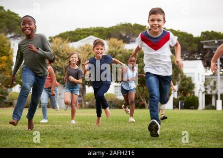 Aufgeregt Grundschülern über Feld in den Pausen laufen Stockfoto