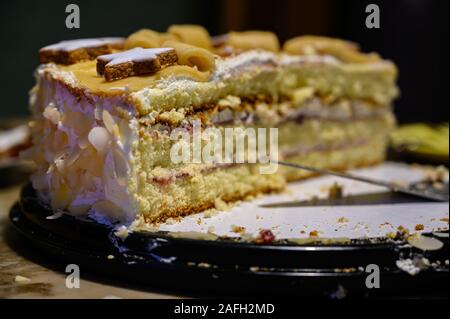 Nahaufnahme eines mehrschichtigen Kuchens mit Dekorationen auf einem Teller Mit einem Kuchenserver darauf Stockfoto
